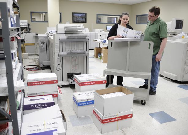 In this Wednesday, April 1, 2015 photo, Bill Lewis, right, looks over a copy with colleague Rosie Rivera at CMS Mailing, in Monroe, Conn. Lewis was hired by CMS Mailing through Platform To Employment, a nonprofit program that offers to pay some long-term unemployed workers' salaries for their first 8 weeks on a new job, essentially eliminating the companies' risk of hiring of them. (AP Photo/Jessica Hill)